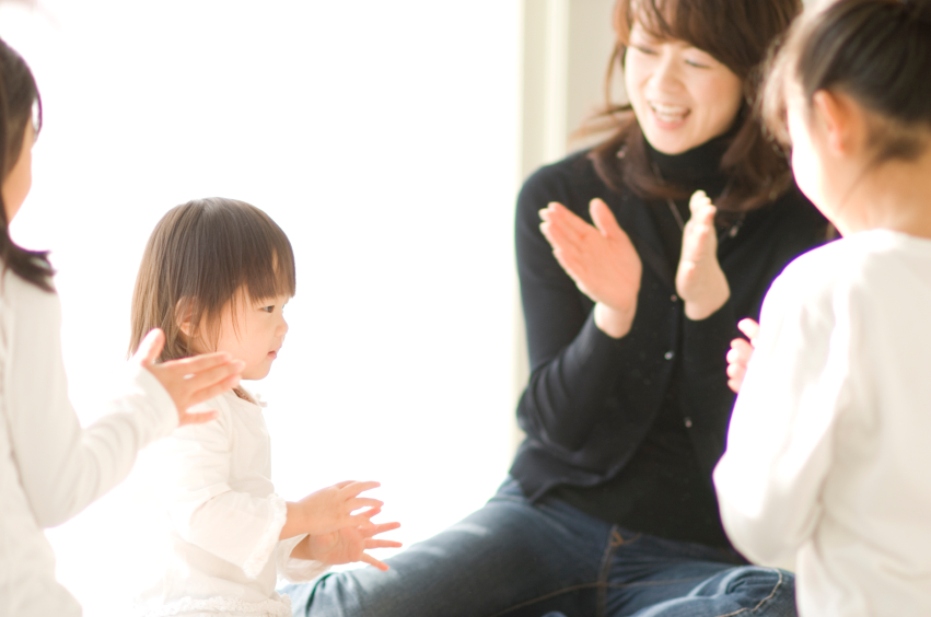 Three Japanese sisters and mother clapping their hands and playing
